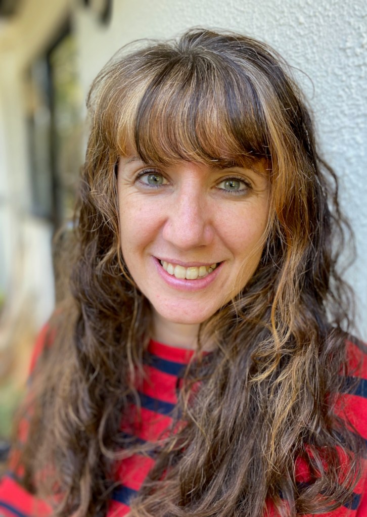 Profile picture of a woman with long brown hair, wearing a red and navy striped t-shirt. 
